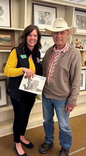 A photo by Kathy Shirilla. Done Greytak, artist, and Jane Woolery, Director of the Montana 4-H Foundation smile while holding the calendar that Greytak creates for the foundations annually.